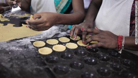 Bakery staff assemble pie shells for mini-chocolate tarts.