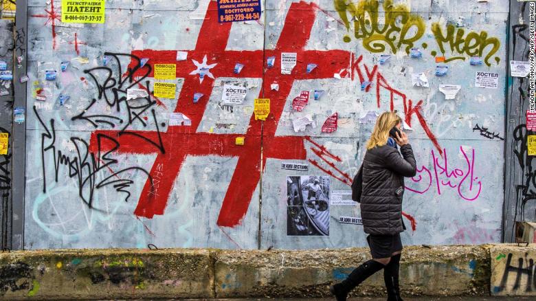 A woman walks past a graffiti covered wall with a giant hashtag sign near Moscow&#39;s Kursky railway station on November 17, 2017.
