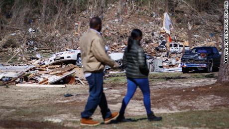 Krystal Stenson-Garrett walks with her husband, Shaun, through the wreckage where her family's homes used to be.