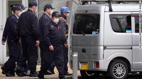 Carlos Ghosn walks into a van with a ladder on its roof.