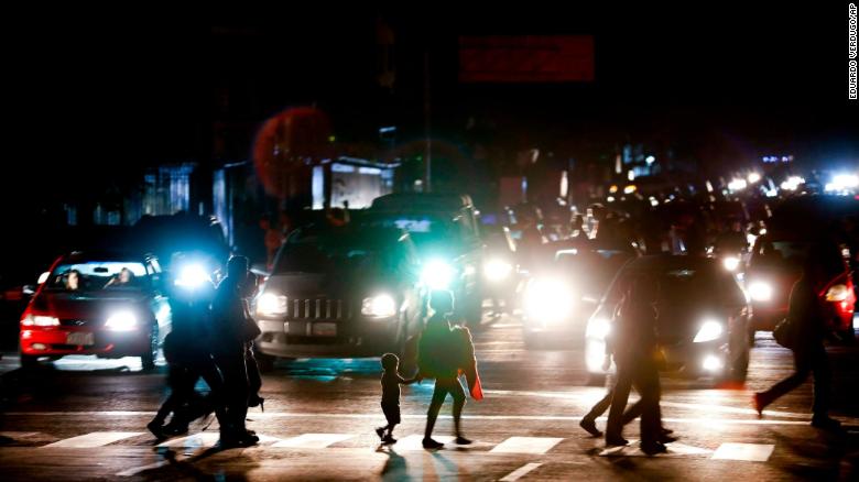 Residents cross a street in the dark after a power outage in Caracas, Venezuela, Thursday, March 7, 2019. A power outage left much of Venezuela in the dark early Thursday evening in what appeared to be one of the largest blackouts yet in a country where power failures have become increasingly common. Crowds of commuters in capital city Caracas were walking home after metro service ground to a halt and traffic snarled as cars struggled to navigate intersections where stoplights were out. (AP Photo/Eduardo Verdugo)