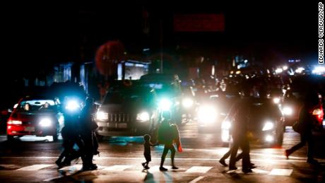 Residents cross a street in the dark after a power outage in Caracas, Venezuela, Thursday, March 7, 2019. A power outage left much of Venezuela in the dark early Thursday evening in what appeared to be one of the largest blackouts yet in a country where power failures have become increasingly common. Crowds of commuters in capital city Caracas were walking home after metro service ground to a halt and traffic snarled as cars struggled to navigate intersections where stoplights were out. (AP Photo/Eduardo Verdugo)