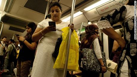 Indian women use their smartphones as they travel in the carriage reserved for women on the metro in New Delhi on July 3, 2015. 