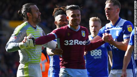 Jack Grealish is helped up after being struck by a fan. 