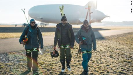 The freeriding trio pose in front of the airship.