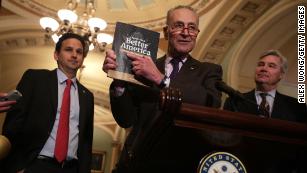 U.S. Senate Minority Leader Sen. Chuck Schumer (D-NY) (2nd L) holds up a copy of U.S. President Donald Trump's FY2020 budget request as Sen. Brian Schatz (D-HI) (L) and Sen. Sheldon Whitehouse (D-RI) (R) look on during a news briefing after the weekly Senate Democratic policy luncheon March 12, 2019 at the U.S. Capitol in Washington, DC.   (Alex Wong/Getty Images)