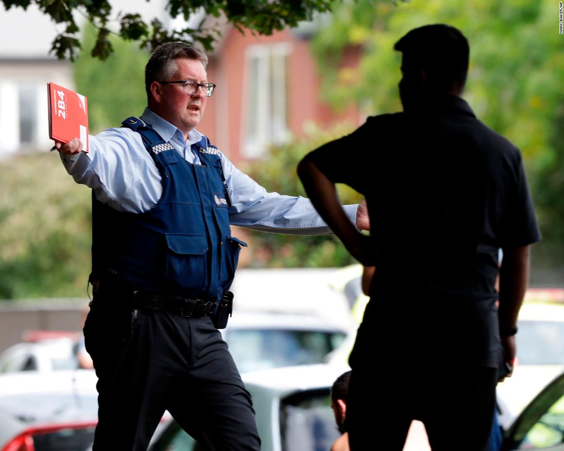 A police officer attempts to move people away from a mosque.