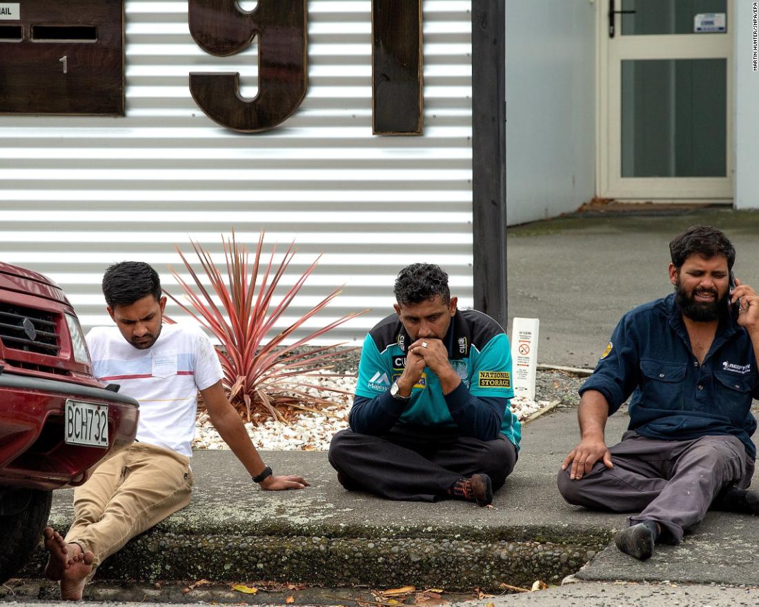 People grieve on a curb in Christchurch.