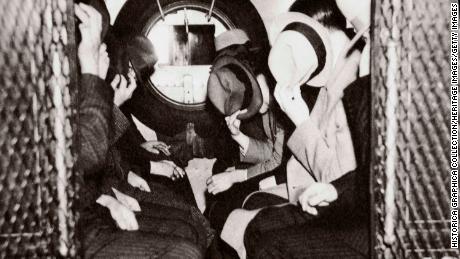 Gangsters in a patrol wagon hiding their faces from the camera as they head to the office of the special prosecutor during the mid-1930s. 