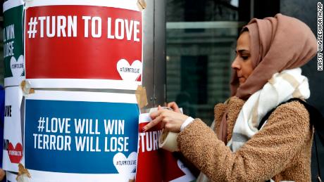 A demonstrator hangs banners from multi-faith group &#39;Turn to Love&#39; during a vigil at New Zealand House in London.
