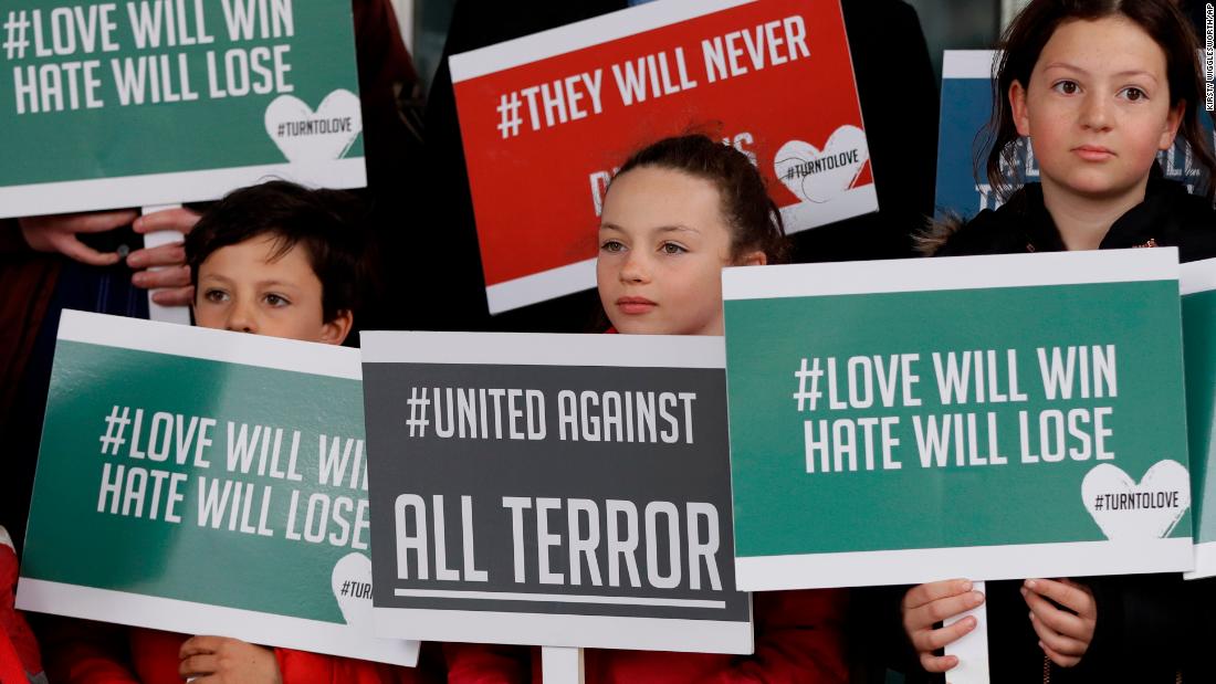 Young demonstrators hold banners from the multifaith group Turn to Love during a vigil at the New Zealand House in London.