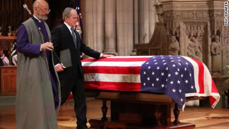 Former President George W. Bush touches his father&#39;s casket after speaking at his memorial service in Washington.