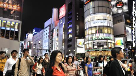Pedestrians cross an intersection in Tokyo&#39;s Ginza district