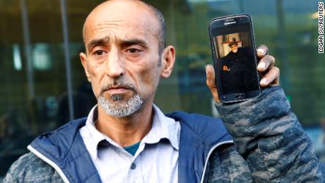 Omar Nabi holds up a phone displaying a photo of his dead father Haji Daoud, at the district court in Christchurch.