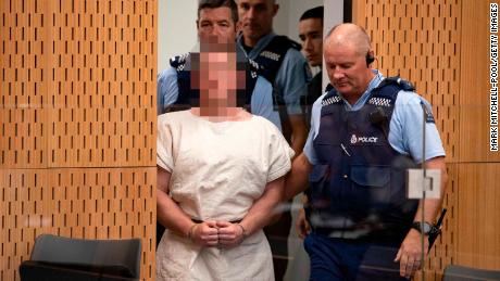 Tarrant is escorted into Christchurch District Court on Saturday. The judge ruled pictures of the suspect in court must have his face blurred.