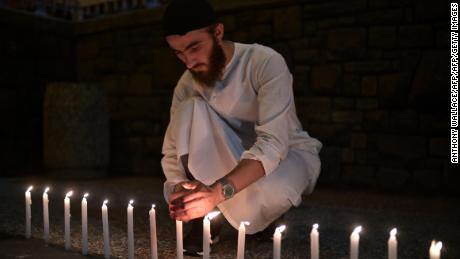 A well-wisher helps light dozens of candles as he pays respects to victims outside the hospital in Christchurch Saturday.