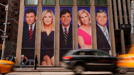 Traffic on Sixth Avenue passes by advertisements featuring Fox News personalities, including Bret Baier, Martha MacCallum, Tucker Carlson, Laura Ingraham, and Sean Hannity, adorn the front of the News Corporation building.