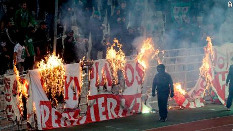 Fans burn a banner in front of the stands during the game, which was ultimately abandoned after 70 minutes due to persistent crowd trouble.
