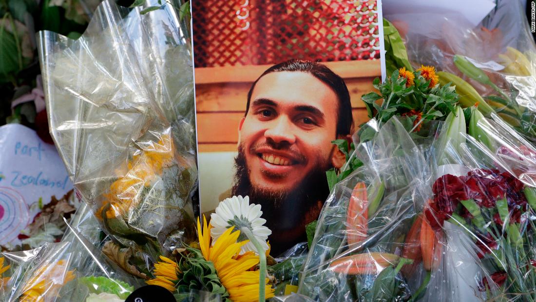 A photo tribute for Christchurch mosque shooting victim Tariq Omar lies amid mounds of flowers across the road from the Al Noor mosque in Christchurch, New Zealand Tuesday, March 19.