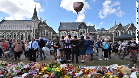 A group of students sings in front of a floral tribute to victims of the mosque shootings in Christchurch.