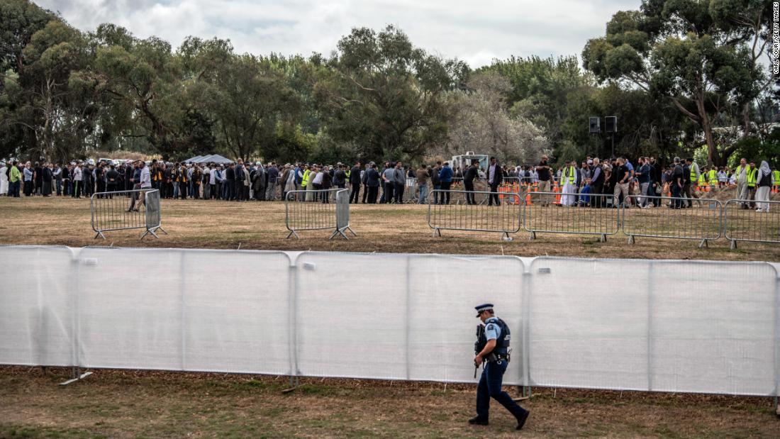 An armed policeman walks alongside a fence at Memorial Park Cemetery as a funeral takes place for two of the victims of the Christchurch attack on March 20 in Christchurch.