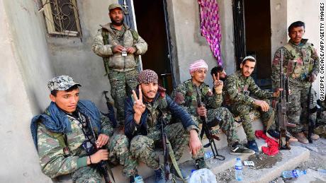 Fighters from the Syrian Democratic Forces returning from the frontline in Baghouz flash the &quot;V&quot; for victory sign.