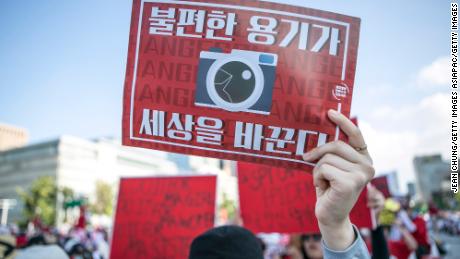 A woman holds up an anti-spy cam poster during a protest in Seoul in 2018. 