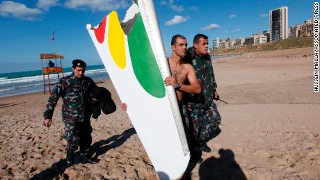 A firefighter carrying a part of the Ethiopian Airlines Boeing 737 that crashed in Lebanon in 2010. 