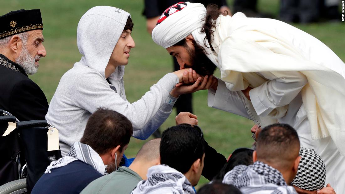 Zaid Mustafa, second left, son and brother of victims from the mosque attacks, is welcomed at Friday prayers at Hagley Park in Christchurch on March 22.