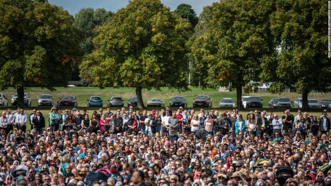 Visitors look on as Muslims attend Friday prayers in a park near Al Noor mosque in Christchurch, New Zealand.