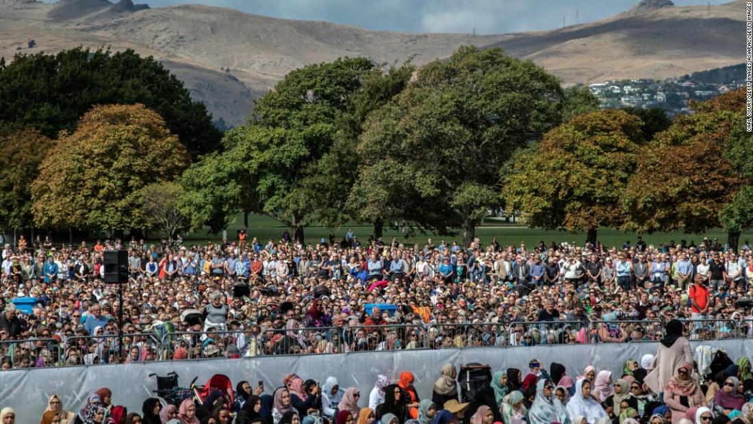  Visitors look on as Muslims attend Friday prayers in a park near Al Noor mosque. 