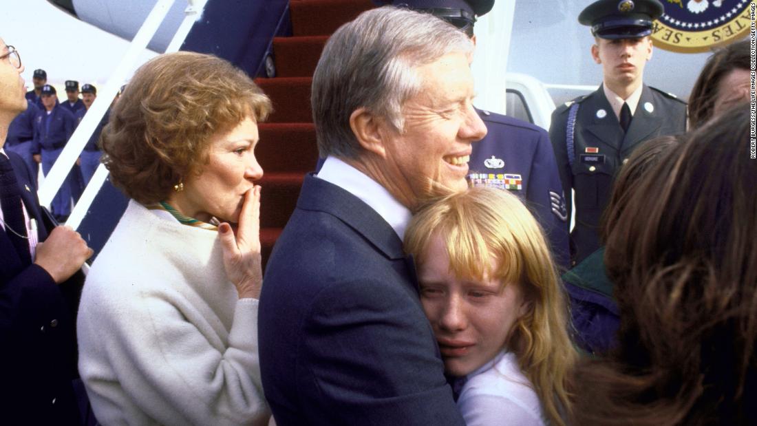 Before departing for Georgia following Reagan&#39;s inauguration, Carter holds his crying daughter as his wife blows a kiss at Andrews Air Force Base in Maryland.