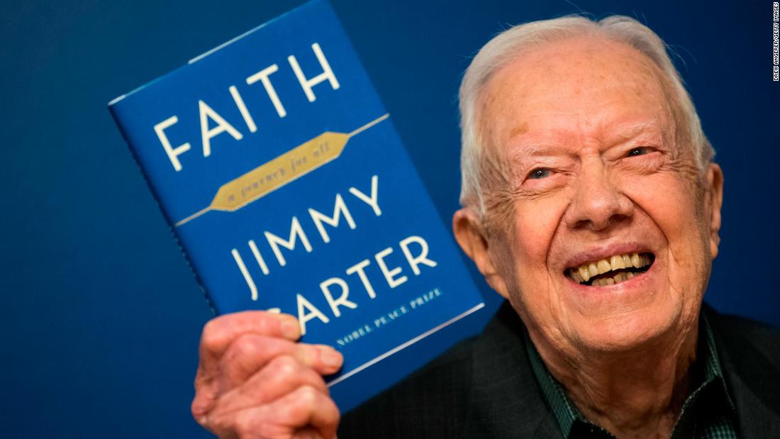 Carter holds up a copy of his new book &quot;Faith: A Journey For All&quot; at a book-signing event in New York in March 2018.
