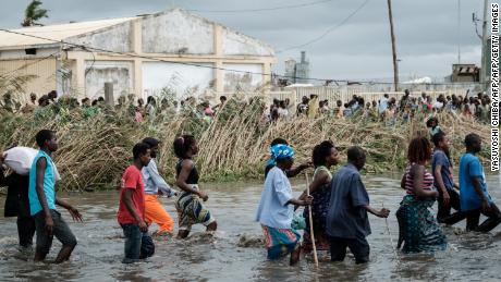 People carry Chinese rice from a warehouse surrounded by water after the Cyclone Idai hit the area, in Beira, Mozambique, on March 20, 2019.