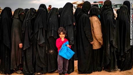 TOPSHOT - Fully-veiled women and children queue at a screening point as hundreds of civilians, who streamed out of the Islamic State group&#39;s last Syrian stronghold, arrive in an area run by US-backed Syrian Democratic Forces outside Baghouz in the eastern Syrian Deir Ezzor province on March 5, 2019. - Shell-shocked and dishevelled, hundreds of women and children stumbled through eastern Syria&#39;s windswept desert carrying what little they could after fleeing the IS group&#39;s final speck of territory. (Photo by Delil SOULEIMAN / AFP)        (Photo credit should read DELIL SOULEIMAN/AFP/Getty Images)