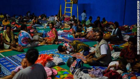 Indonesians displaced by the floods sleep on a badminton court at a local government building in Sentani.