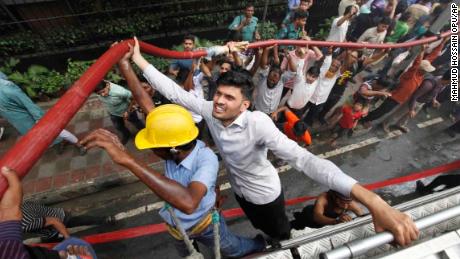 Locals help firefighters douse a fire in the multi-story office building in Dhaka.