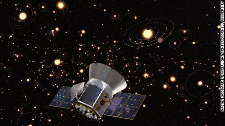 An artist's concept of TESS against a background of stars and orbiting planets in the Milky Way. 