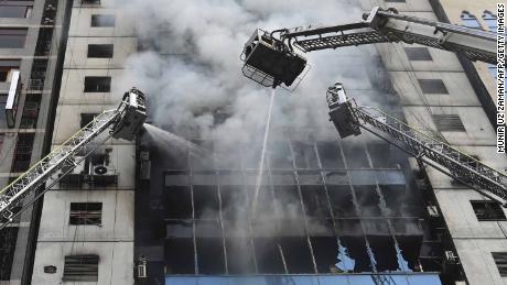 Bangladeshi firefighters on ladders work to extinguish a blaze in an office building in Dhaka on March 28, 2019. - A huge fire tore through a Dhaka office block March 28 killing at least five people with many others feared trapped in the latest major inferno to hit the Bangladesh capital. (Photo by MUNIR UZ ZAMAN / AFP)        (Photo credit should read MUNIR UZ ZAMAN/AFP/Getty Images)