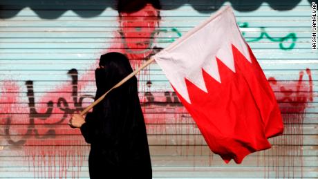 A Bahraini anti-government protester carries the national flag past anti-government graffiti sprayed over by authorities in 2013. 