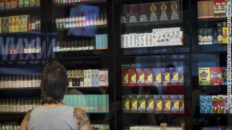 A customer browses various flavored vape juices for electronic cigarettes.