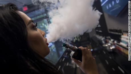 A woman exhales vapor while using an electronic cigarette device.