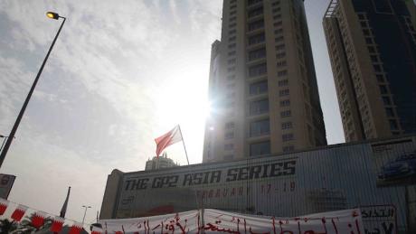 A protest sign is draped over a motorsport advertisement at the now-demolished Pearl Monument in Manama, during the 2011 Arab Spring protests. 