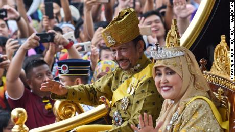 TOPSHOT - Brunei&#39;s Sultan Hassanal Bolkiah and Queen Saleha ride in a royal chariot during a procession to mark his golden jubilee of accession to the throne in Bandar Seri Begawan on October 5, 2017. 
Brunei&#39;s all-powerful sultan marks 50 years on the throne on October 5 with lavish celebrations including a glittering procession, a 21-gun salute and a ceremony at his vast, golden-domed palace. / AFP PHOTO / Roslan RAHMAN        (Photo credit should read ROSLAN RAHMAN/AFP/Getty Images)