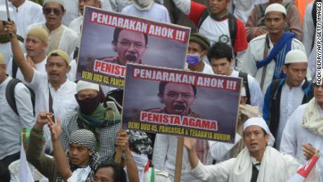 Indonesian Muslim demonstrators, holding banners that read &quot;put Ahok in jail,&quot; march towards the presidential palace in Jakarta on November 4, 2016.