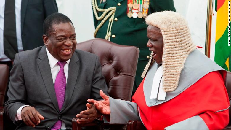 Zimbabwe's President Emmerson Mnangagwa, left, shakes hands with the country's chief justice Luke Malaba.