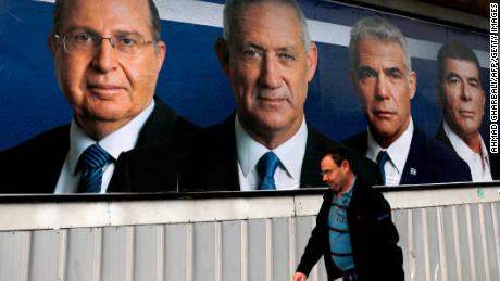 An Israeli Arab man walks past an electoral billboard bearing portraits of Blue and White political alliance leaders (from left) Moshe Yaalon, Benny Gantz, Yair Lapid and Gabi Ashkenazi.