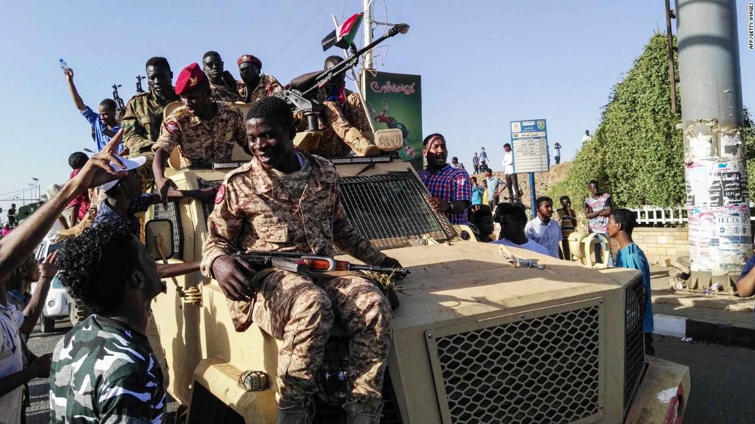 Protesters sit atop a military vehicle as soldiers stand nearby on April 7.