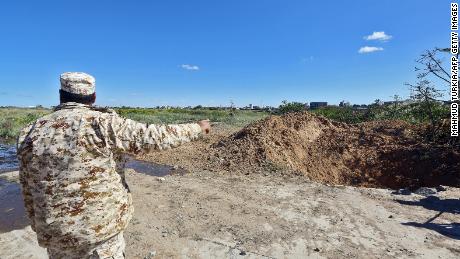 A member of the Libyan security forces points towards a crater on the ground following an air strike at Mitiga International Airport in the capital Tripoli on April 8, 2019. 