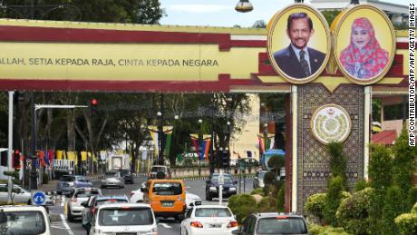 Portraits of Brunei&#39;s Sultan Hassanal Bolkiah and Queen Saleha are seen beside a slogan (partially cutoff) in Bahasa Melayu that reads &quot;Obedience to Allah, loyalty to the king, love for the country&quot; in Bandar Seri Begawan on October 4, 2017. 